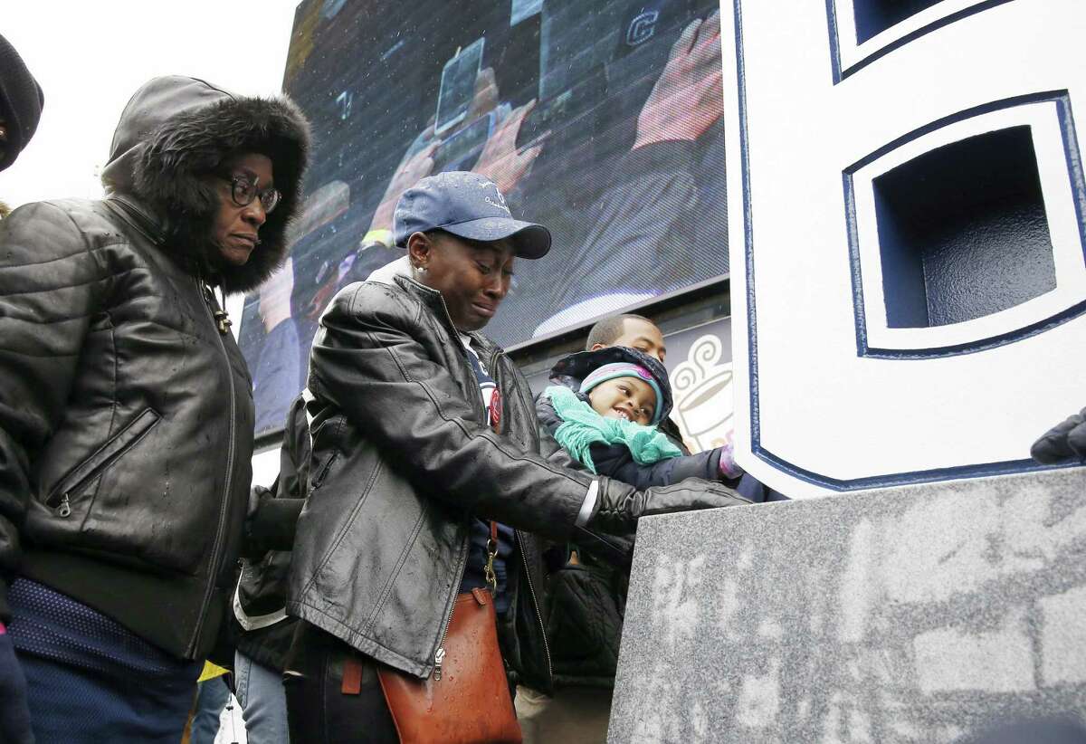 Former UConn player Jasper Howard’s mother, Joangila Howard, second from left, and his grandmother Vicki Ross, left, bow their heads after the unveiling of a memorial to Jasper during halftime of the Huskies’ 37-29 win over Central Florida on Saturday at Rentschler Field in East Hartford.