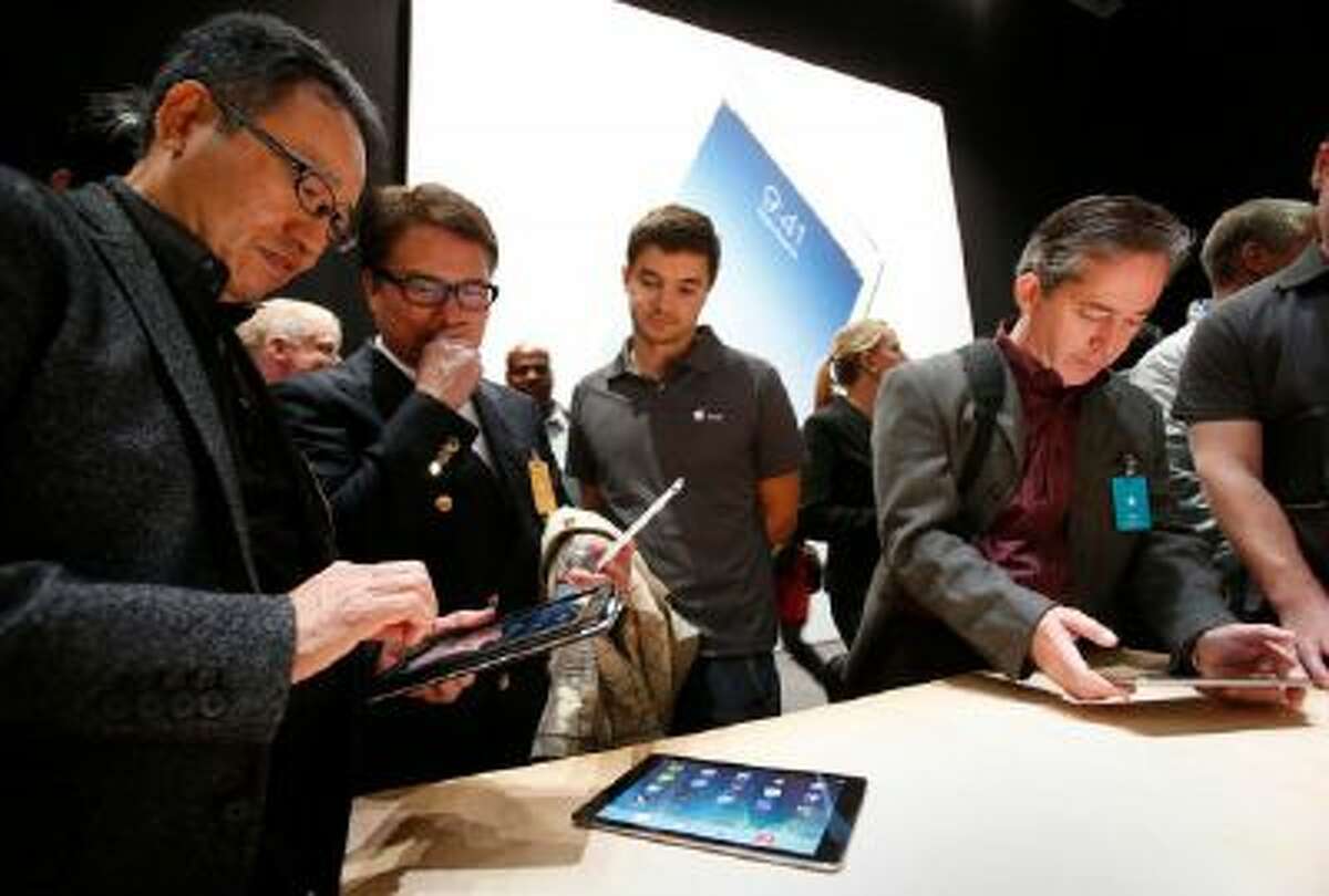 Tech reporters paw Apple's new iPad models Tuesday Oct. 22, 2013 in San Francisco, Calif., after the Cupertino-based company announced its latest release, the iPad Air, a 10-inch tablet with a thinner body and a new iPad Mini with high-definition "Retina" display.