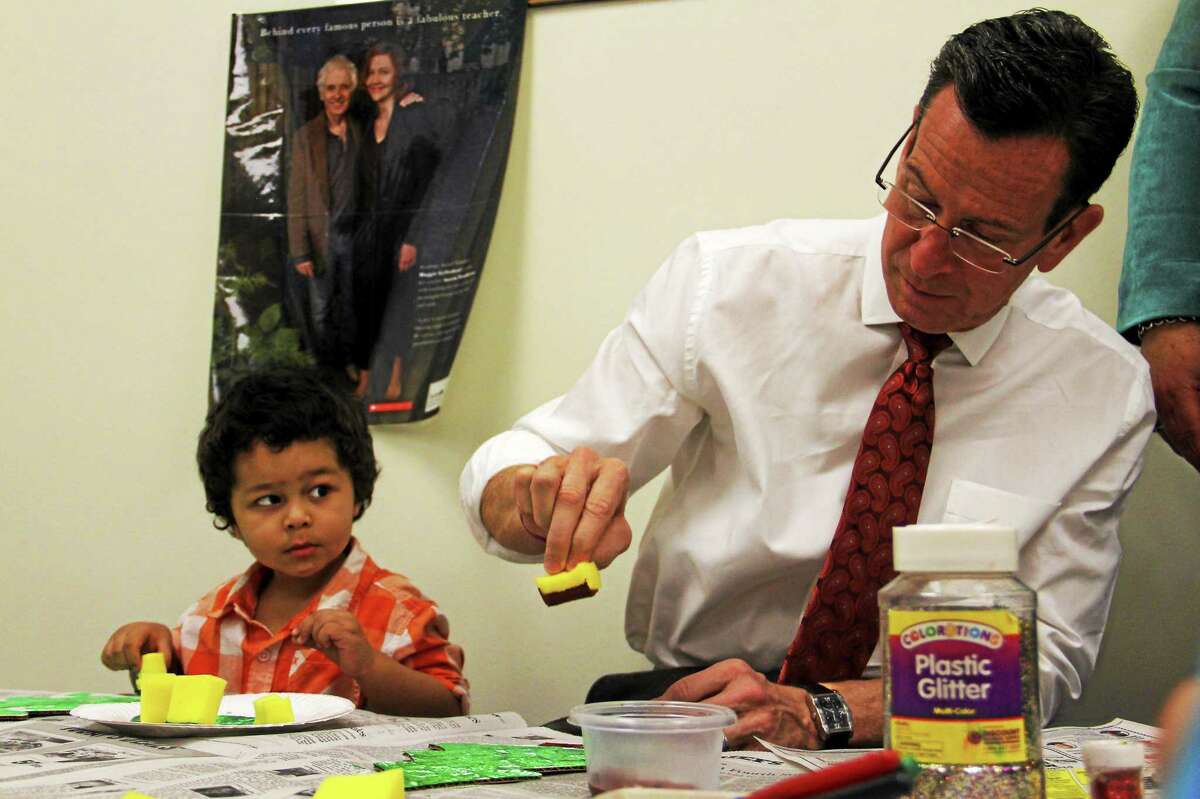 Marcelo Ferreira, 3, watches Gov. Dannel Malloy paint a Christmas tree on Friday, Dec. 19, at the Torrington Child Care Center. Malloy stopped by along with a Congressional delegation to promote $12.5 in federal funding to help expand preschool services, including the Child Care Center, in the state. Esteban L. Hernandez Register Citizen