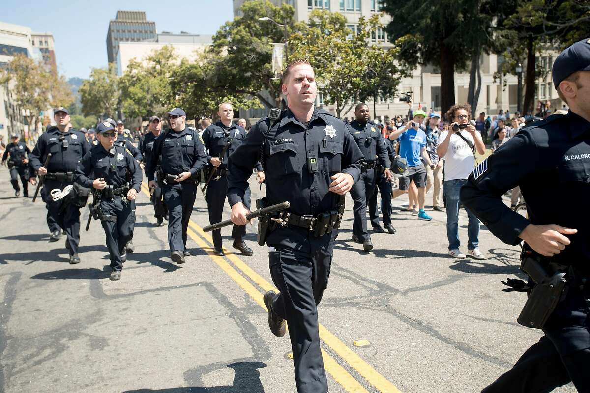 Police officers run to help a man injured by protesters against conservative demonstrators in Martin Luther King Jr. Civic Center Park on Sunday, Aug. 27, 2017, in Berkeley, Calif. The conservatives had planned a "No Marxism in America" gathering.