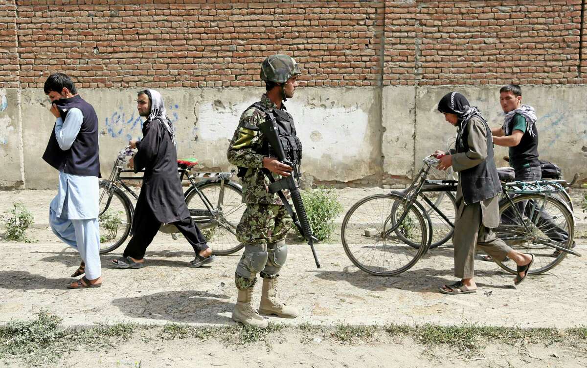 Afghanistan's National Army (ANA) soldier, center, stands guard at the site of a suicide attack in Kabul, Afghanistan, Wednesday, July 2, 2014. A suicide bomber attacked an air force bus in Kabul, early Wednesday, killing at least four people, security officials said. (AP Photo/Rahmat Gul)