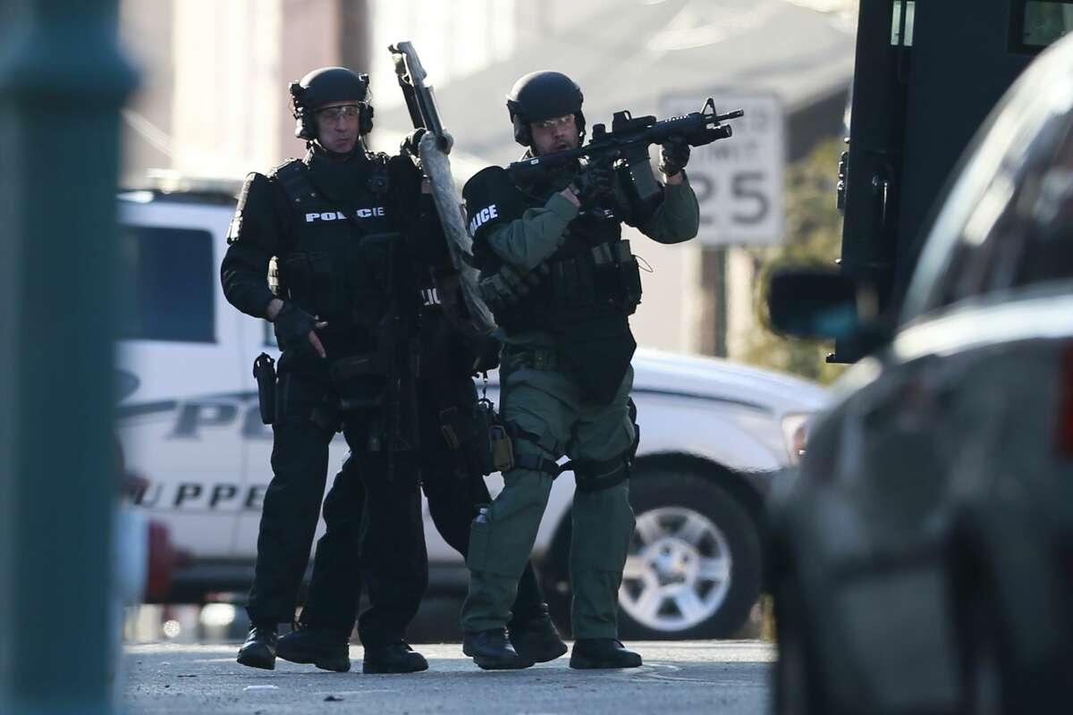 Police gather near a home, Monday, Dec. 15, 2014, in Souderton, Pa., where suspect Bradley William Stone is believed to have barricaded himself inside after shootings at multiple homes. The man killed six people and seriously wounded another in three different homes outside Philadelphia and remained at large hours after the shootings, authorities said Monday.