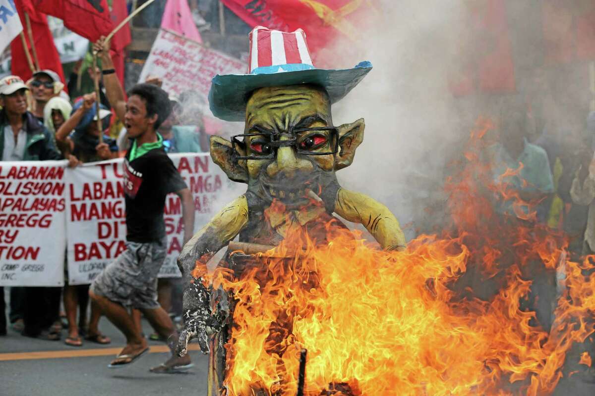 A Filipino activist runs beside a burning effigy of Philippine President Benigno Aquino III as protesters try to get near his house. His stance on agrarian issues has also made him unpopular with farmers.