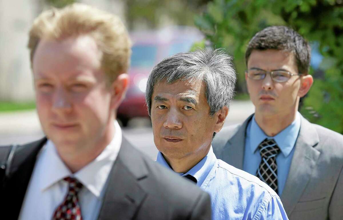 Former Iowa State University researcher Dong-Pyou Han, center, leaves the federal courthouse with his attorney Joe Herrold, left, Tuesday, July 1, 2014, in Des Moines, Iowa. Han was making his initial court appearance on charges that he falsified data to make a proposed AIDS vaccine appear promising and win millions of dollars in federal grant money. (AP Photo/Charlie Neibergall)
