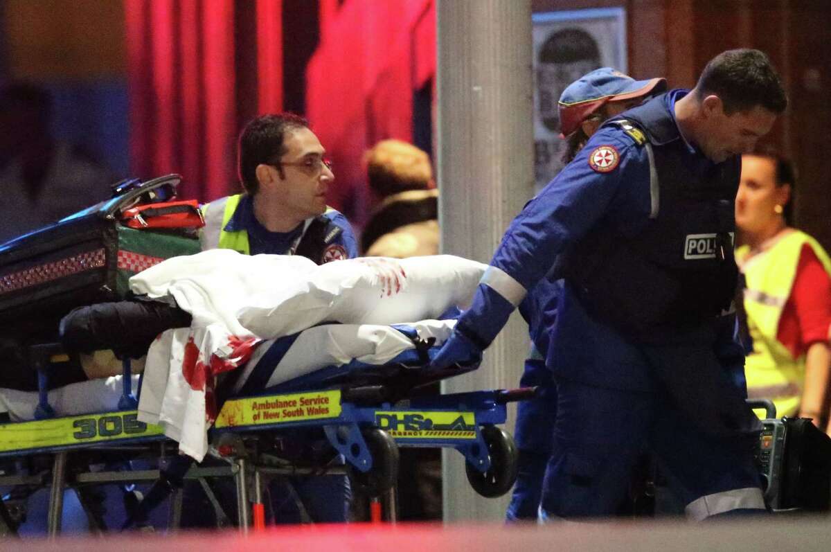 A blood soaked stretcher is wheeled to an ambulance after shots were fired Tuesday during a cafe under seige at Martin Place in the central business district of Sydney, Australia. A flurry of loud bangs erupted as a swarm of heavily armed police stormed inside a downtown Sydney chocolate cafe where a gunman had been holding an unknown number of people hostage for more than 16 hours.