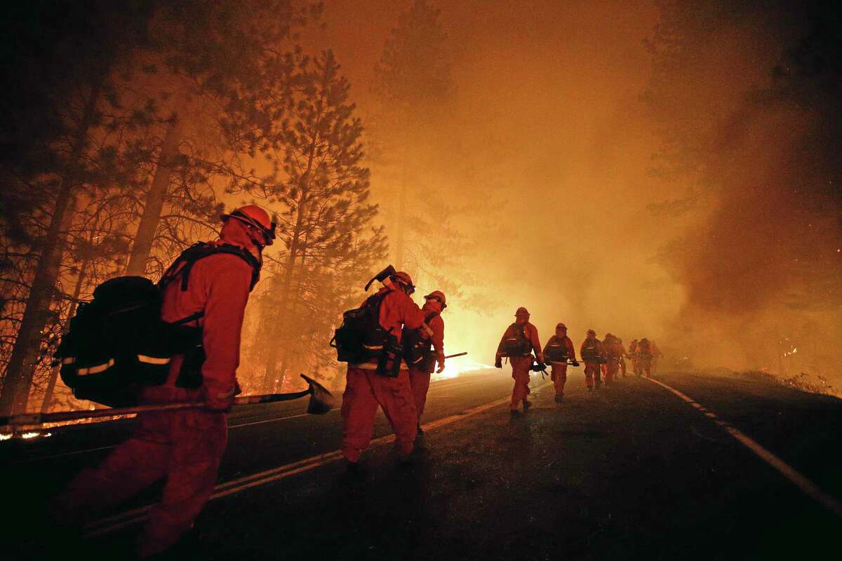 Inmate firefighters walk along Highway 120 after a burnout operation as firefighters continue to battle the Rim Fire near Yosemite National Park, Calif., on Sunday, Aug. 25, 2013. Fire crews are clearing brush and setting sprinklers to protect two groves of giant sequoias as a massive week-old wildfire rages along the remote northwest edge of Yosemite National Park. (AP Photo/Jae C. Hong)