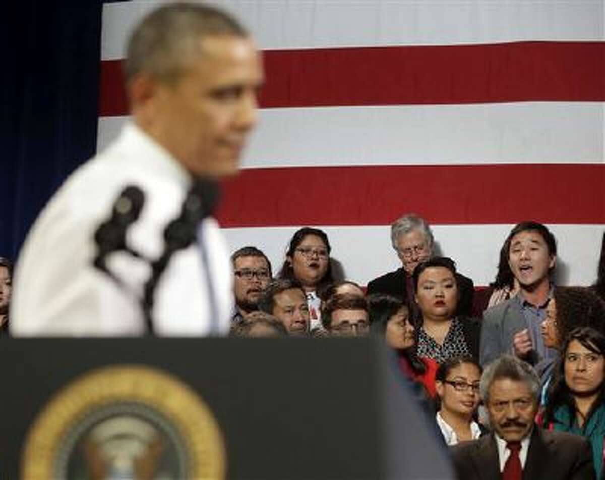 President Barack Obama, left, stops his speech and turns around in response to an unidentified man, right, who heckled him about anti-deportation policies in San Francisco. 2013 was a tough year for Obama on many fronts.