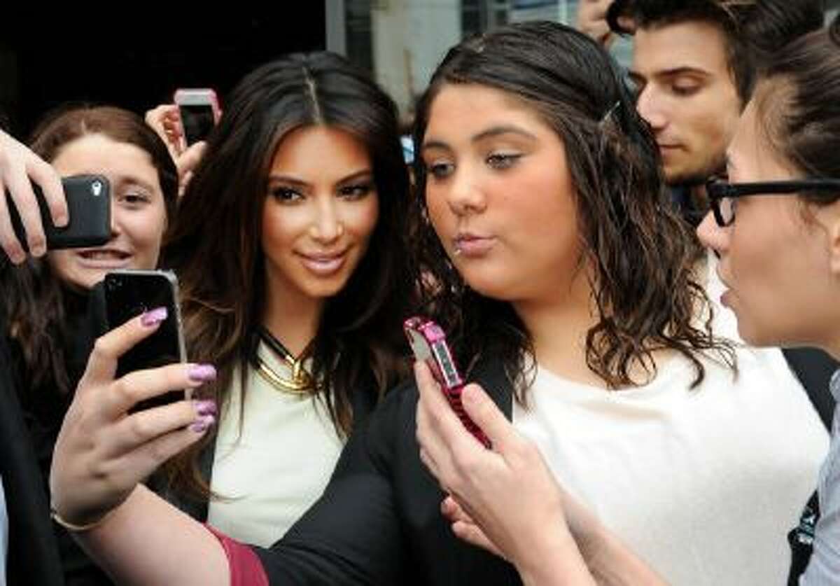 Kim Kardashian, left, take part in a selfie with a fan in Melbourne, Australia. "Selfie" the smartphone self-portrait has been declared word of the year for 2013 by Britain's Oxford University Press.
