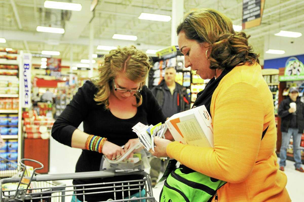 The “Crazy Coupon Chick” Missie Morris, of Torrington, left, and Nicole Lubrico, of Bristol, search through their coupons during a “Coupon Olympics” event at the Torrington Price Chopper Tuesday. All items purchased during the event will be donated to the Feed the Need organization.
