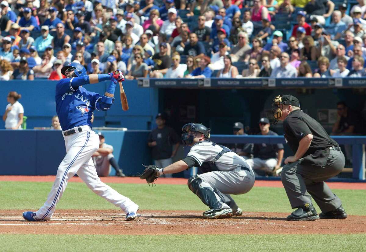 The Blue Jays’ Jose Bautista, left, hits a two run home run in the first inning Saturday.
