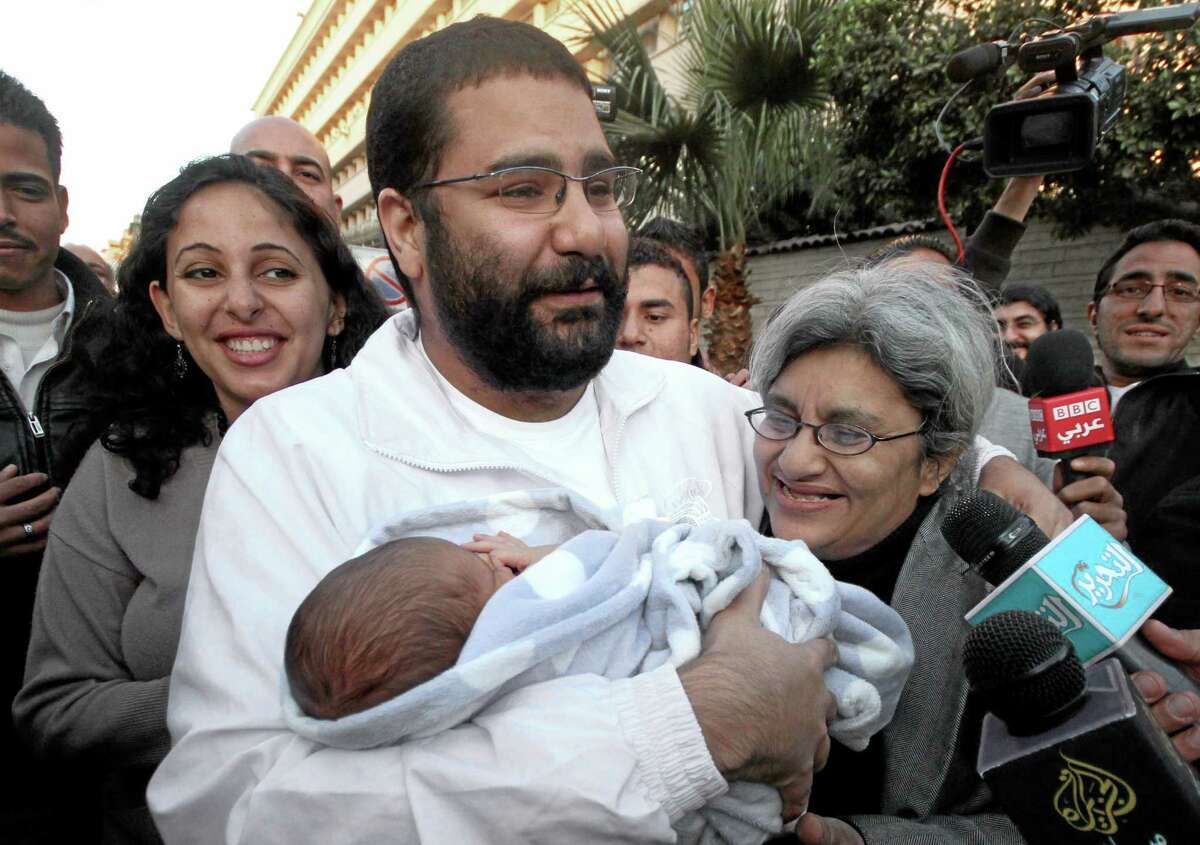 FILE - In this Sunday, Dec. 25, 2011 file photo, Egyptian prominent blogger Alaa Abdel-Fattah, center, hugs his recently born son, Khaled, his mother Laila Soueif, and his sister Ahdaf Soueif, left, after his release, in Cairo, Egypt. An Egyptian court has ordered Abdel-Fattah who has spent nearly four months in jail to be released on bail. Egyptian authorities detained Abdel-Fattah, a leading figure in the 2011 uprising against Hosni Mubarak, in November, and charged him with organizing a protest without permission and assaulting police. (AP Photo/Amr Hafez, File)