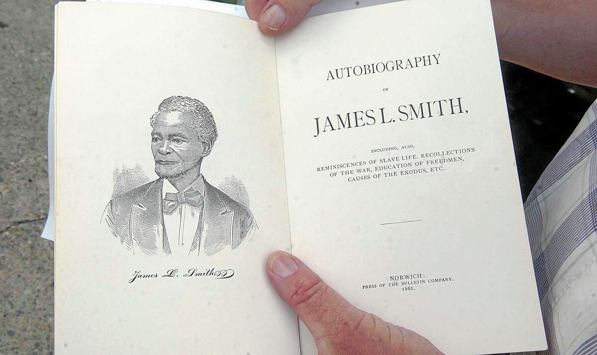 In this July 24, 2013 photo, historian Dale Plummer holds the autobiography of escaped slave James L. Smith, who bought a home at 59 School Street in Norwich, Conn., in 1848. The city recently acquired the house where Smith lived in freedom and remarkable prosperity. (AP Photo/Norwich Bulletin, John Shishmanian)
