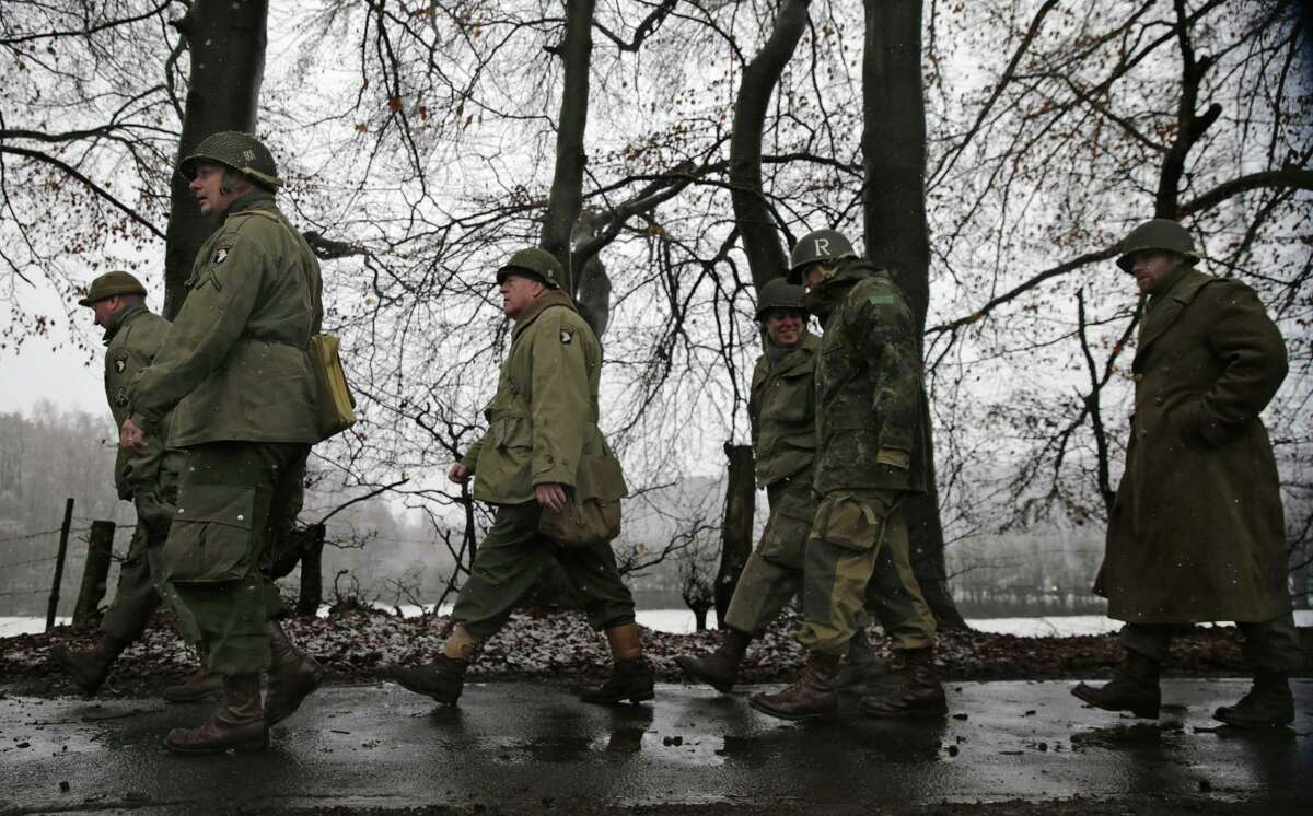 Re-enactors dressed as US WWII soldiers walk along a road during the 70th anniversary of the Battle of the Bulge or the Ardennes Offensive, in Bastogne, southeastern Belgium, Saturday, Dec. 13, 2014. The Battle of the Bulge was fought in dense forests and narrow valleys of the Belgian and Luxembourg Ardennes and was one of the bloodiest battles of World War II. (AP Photo/Yves Logghe)