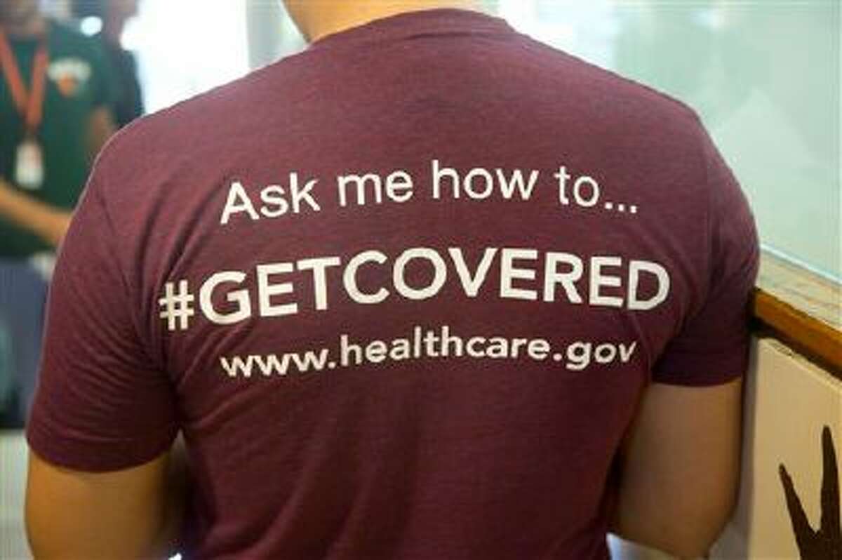 In this March 15, 2014 photo,a volunteer health care worker wears a t-shirt, getting people to sign up for the new health care programs. As federal health officials are aggressively courting young adults to sign up for health insurance with celebrity endorsement and social media campaigns, they are also getting significant help from the very demographic they're targeting. Medical, nursing and law students across Florida are getting certified as counselors and are staffing enrollment events as the March 31 deadline to sign up for insurance under the Affordable Care Act looms. (AP Photo/J Pat Carter)