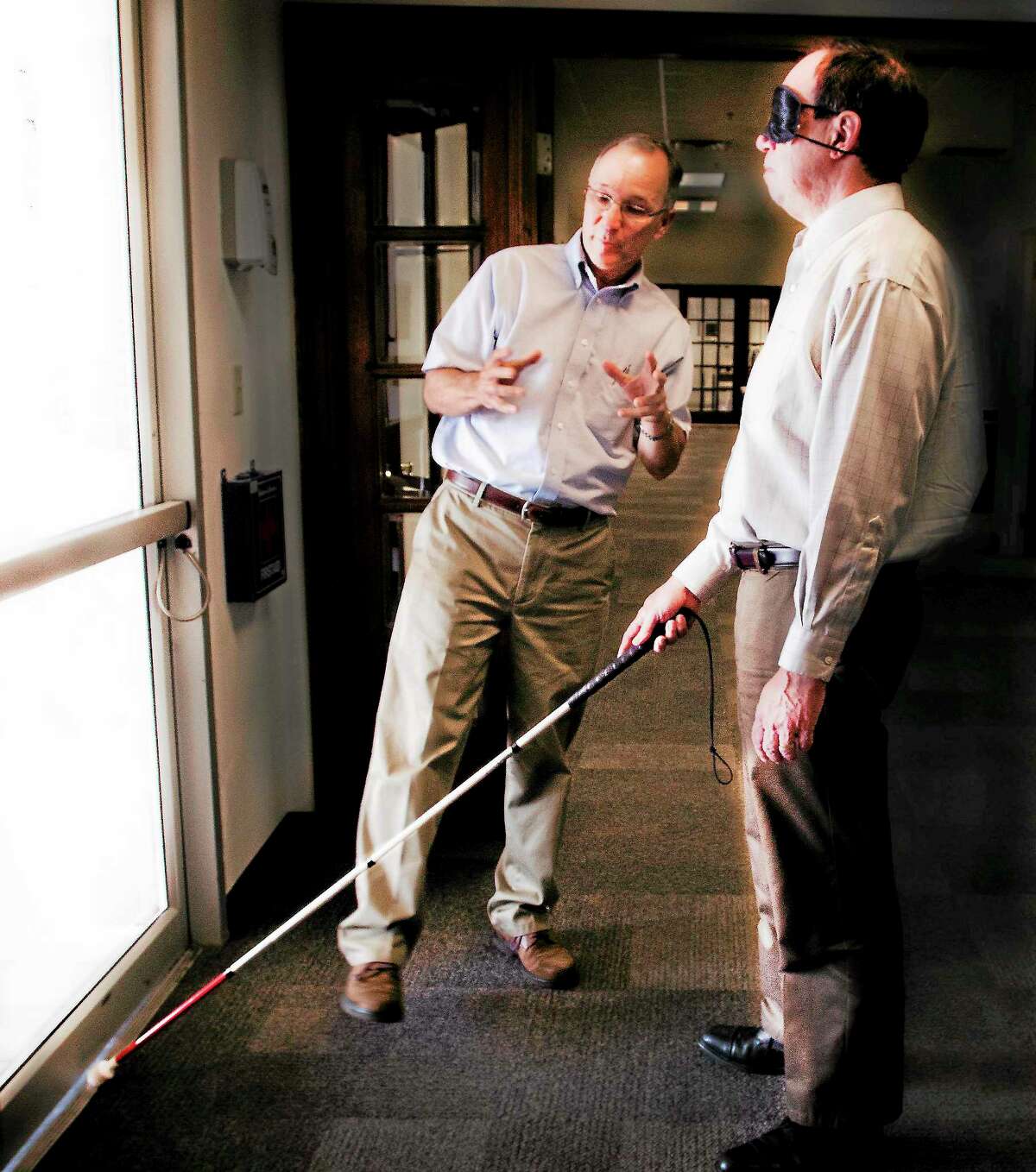Melanie Stengel — Register John Waiculonis (L) guides reporter Ed Stannard as he learns how to navigate a doorway while blindfolded 8/20.