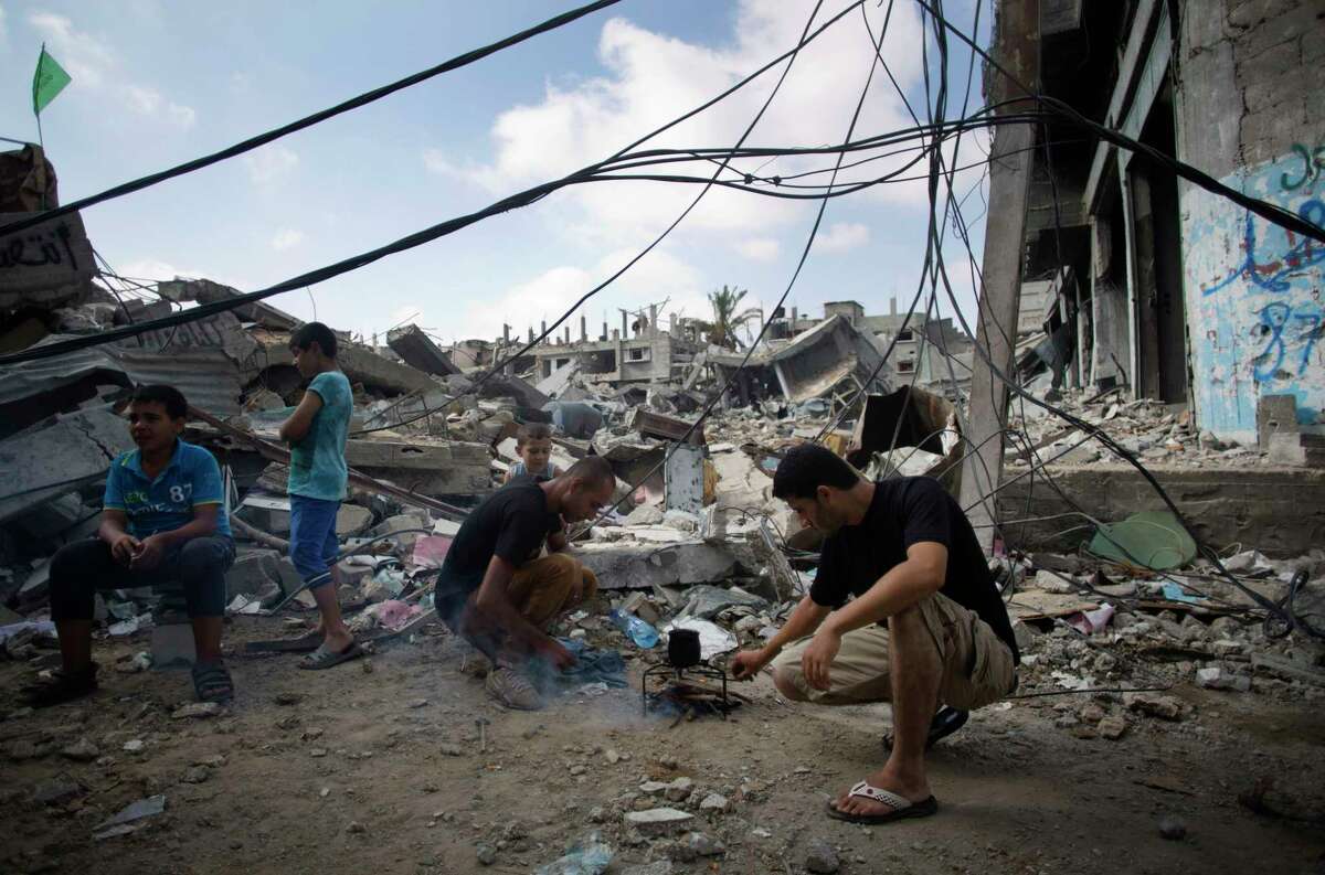 Palestinians make coffee next to their destroyed house in Gaza City's Shijaiyah neighborhood, Wednesday, Aug. 27, 2014. The third Gaza War in six years appears to have ended in another sort of tie, with both Israel and Hamas claiming the upper hand. Their questionable achievements have come at a big price, especially to long-suffering Palestinians in Gaza. (AP Photo/Khalil Hamra)