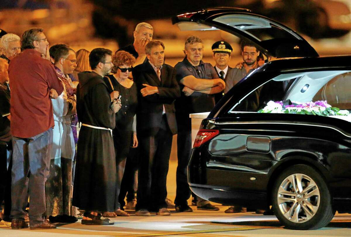 Maria Daniela, fifth right, and Pier Luigi Camilli, fourth right, parents of Associated Press video journalist Simone Camilli, stand in front of the coffin of their son, upon its arrival at Ciampino's military airport, on the outskirts of Rome, Thursday, Aug. 14, 2014. Six people, including an Associated Press video journalist, were killed Wednesday when leftover ordnance believed to have been dropped in an Israeli airstrike blew up in the Gaza Strip. Simone Camilli and his Palestinian translator, Ali Shehda Abu Afash, were covering the aftermath of the war between Israel and Islamic militants in Gaza when they were killed. The blast occurred as Gaza police engineers were trying to defuse unexploded ordnance fired by Israel. (AP Photo/Riccardo De Luca)