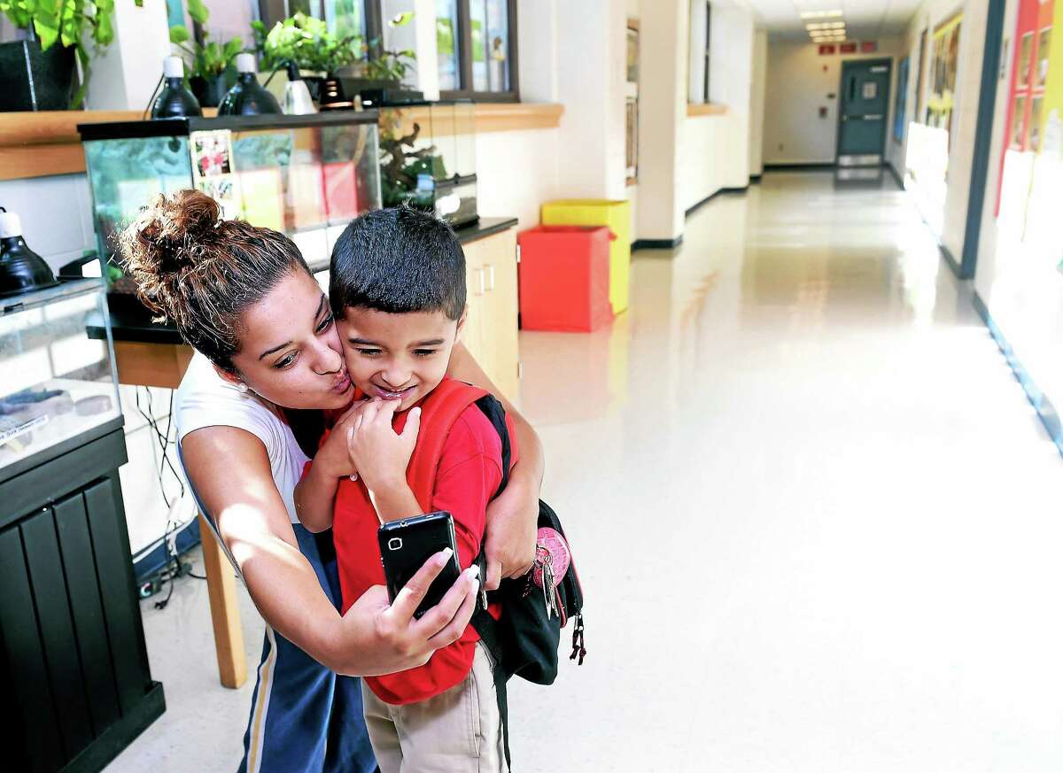 (Arnold Gold-New Haven Register) Keila Vasquez takes a photograph with her first grade son, Wilson, 5, on the first day of school at Mauro-Sheridan Interdistrict Magnet School for Science, Technology & Communications in New Haven on 8/28/2014.