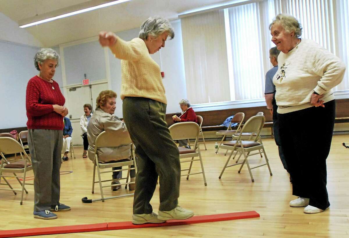 Shirley Ristau, right, coaches Johanna O’Neill, center, through a balance obstacle course while O’Neill’s sister, Mary O’Neill, left, looks on during a fall prevention demonstration class at the Manchester Senior Center in Manchester, Conn.