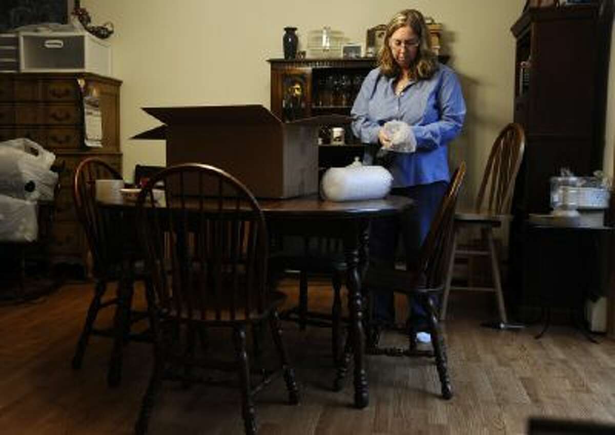 In this Dec. 23, 2013 photo, Leslie Lynch packs up belongings in her dining room in Glastonbury, Conn. Lynch who lost her job last year is moving out of her home of 21 years because she can no longer afford the mortgage payments.