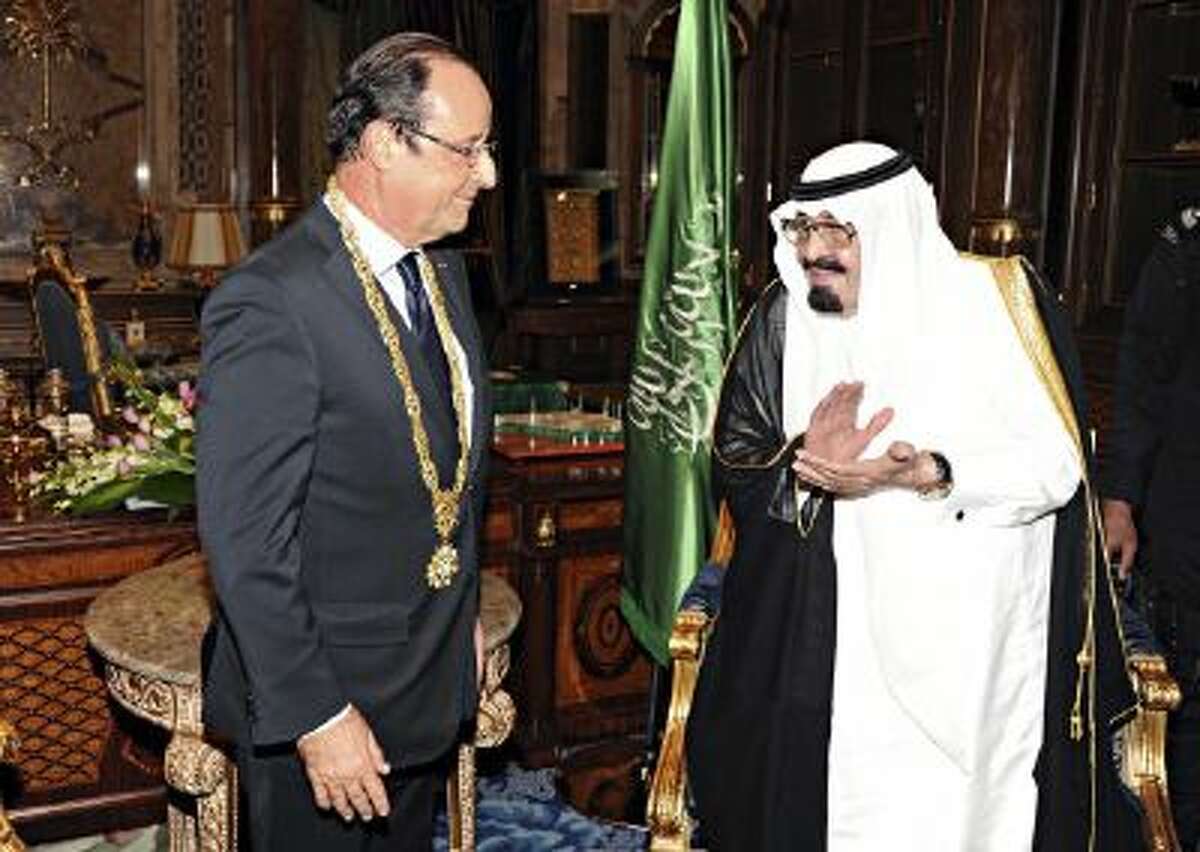 In this Nov. 4, 2012 file photo released by Saudi Press Agency, King Abdullah of Saudi Arabia, right, applauds French President Francois Hollande, left, after presenting him with the Order of Merit in Jiddah, Saudi Arabia.