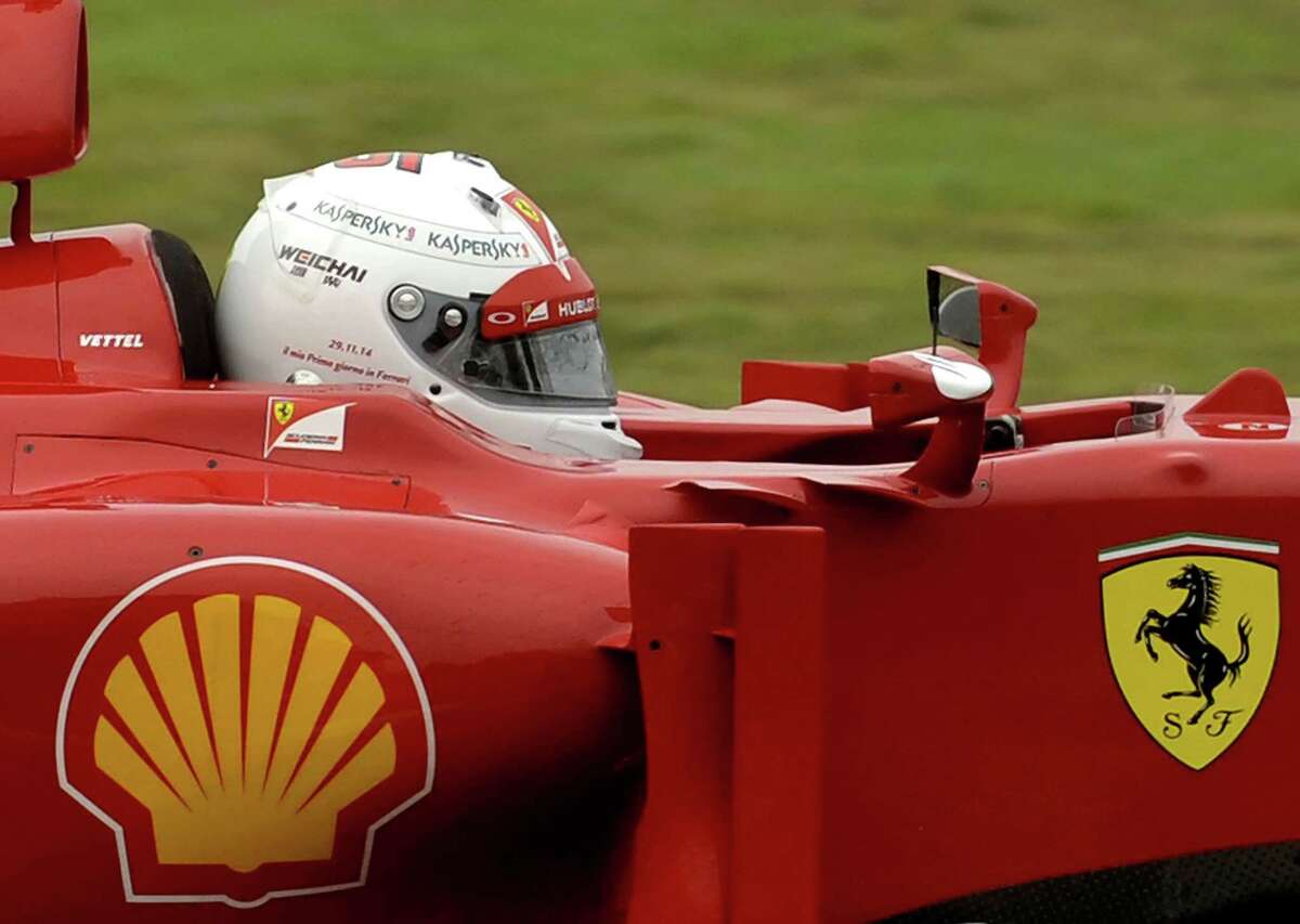 FILE -- In this Nov. 29, 2014 file photo, Sebastian Vettel wears a white helmet with the words, "My first day at Ferrari" plus the date, written on it, as he steers an F2012 car from two seasons ago, at Ferrari's private Fiorano circuit. Ferrariís sleek sports cars and souped-up Formula 1 racing machines have made the prancing horse logo among the worldís most powerful brands. Now, as the company prepares for a public listing, it wants to cash in on the cachet. (AP Photo/Marco Vasini)