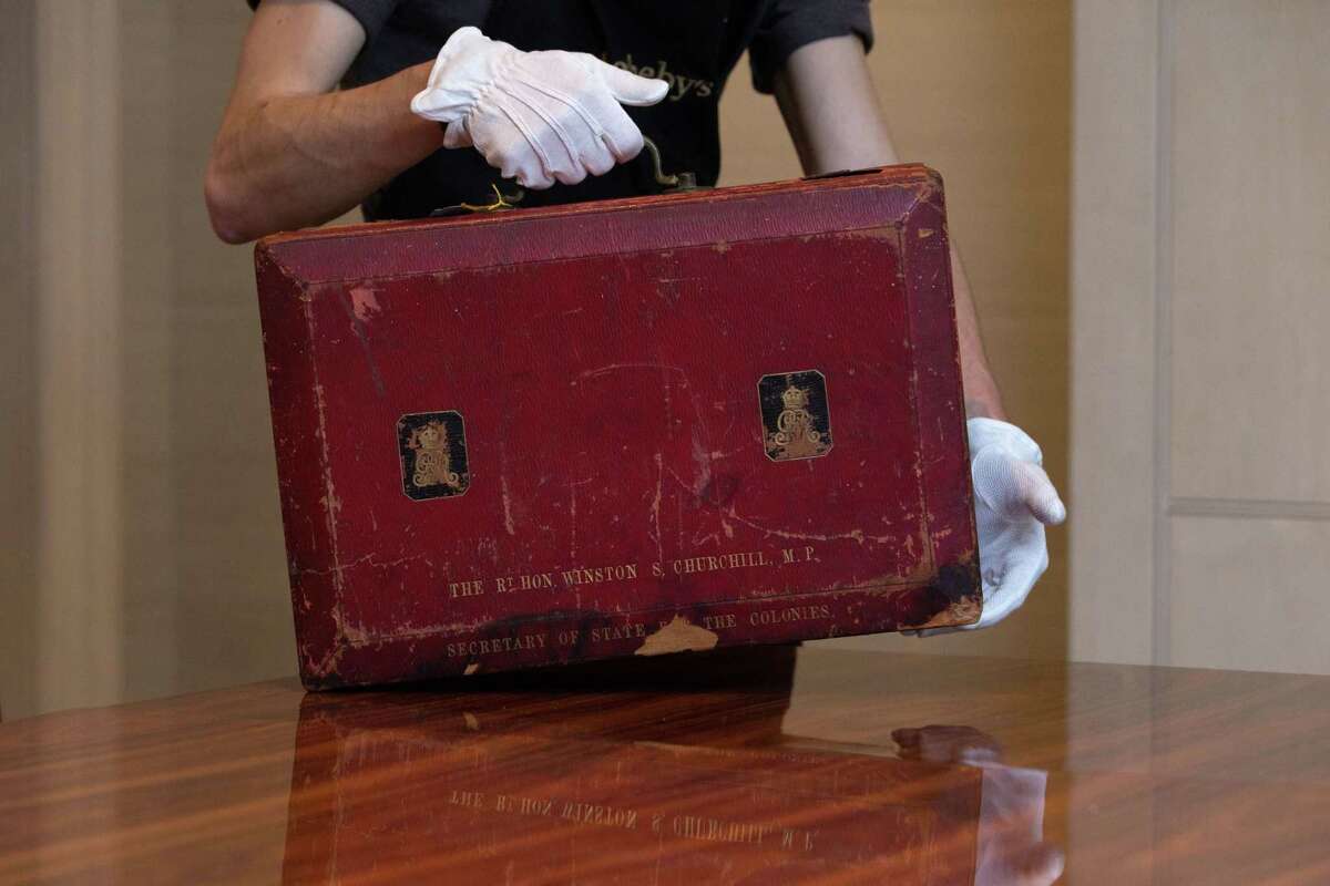 In this photo taken Dec. 9, 2014, a member of Sotheby’s staff poses for a picture with Churchillís red morocco leather dispatch box from his time as Secretary of State for The Colonies: the lid stamped ‘THE RT HON WINSTON CHURCHILL. MP SECRETARY OF STATE FOR THE COLONIES’ at the auction house in London, England.