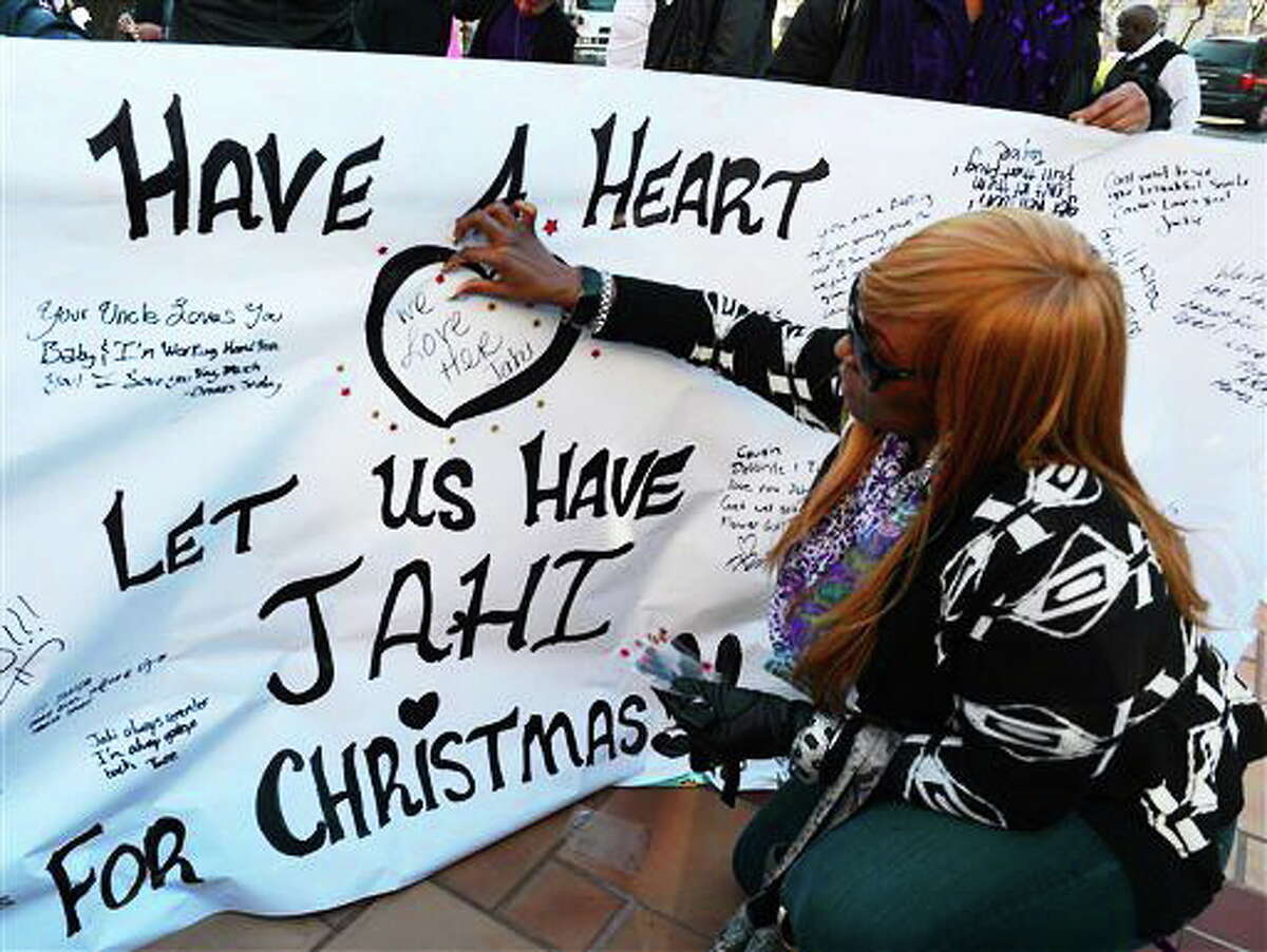 Dede Logan, of Oakland, adds red stars to a poster in support of Jahi McMath in front of Children's Hospital Oakland in Oakland, Calif., on Monday, Dec. 23, 2013. McMath was declared brain dead after experiencing complications following a tonsillectomy at the hospital. (AP Photo/The Contra Costa Times-Bay Area News Group, Susan Tripp Pollard)