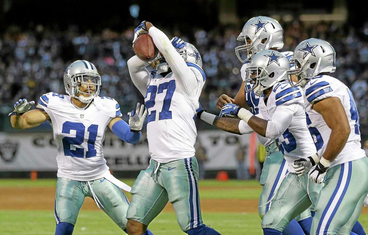 Dallas Cowboys defensive back J.J. Wilcox (27) celebrates with cornerback Sterling Moore (21) and teammates after intercepting a pass from Oakland Raiders quarterback Terrelle Pryor during the second quarter of an NFL preseason football game in Oakland, Calif., Friday, Aug. 9, 2013. (AP Photo/Marcio Jose Sanchez)