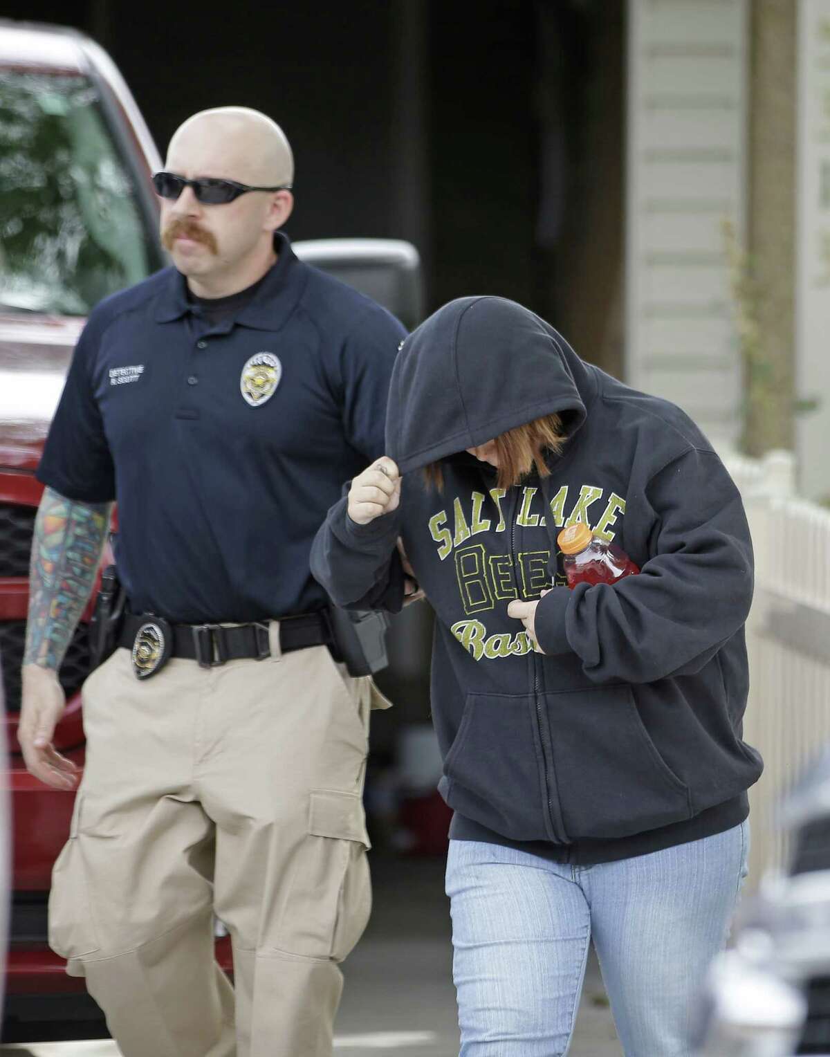 A unidentified woman is escorted from a home by a police officer after a baby was found in a garbage can in Kearns, Utah on Tuesday, Aug. 26, 2014.