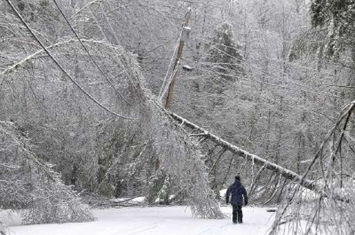 Karen Gibbs walks through a labyrinth of icy broken trees and downed power lines to her home in Belgrade, Maine on Thursday, Dec. 26, 2013.