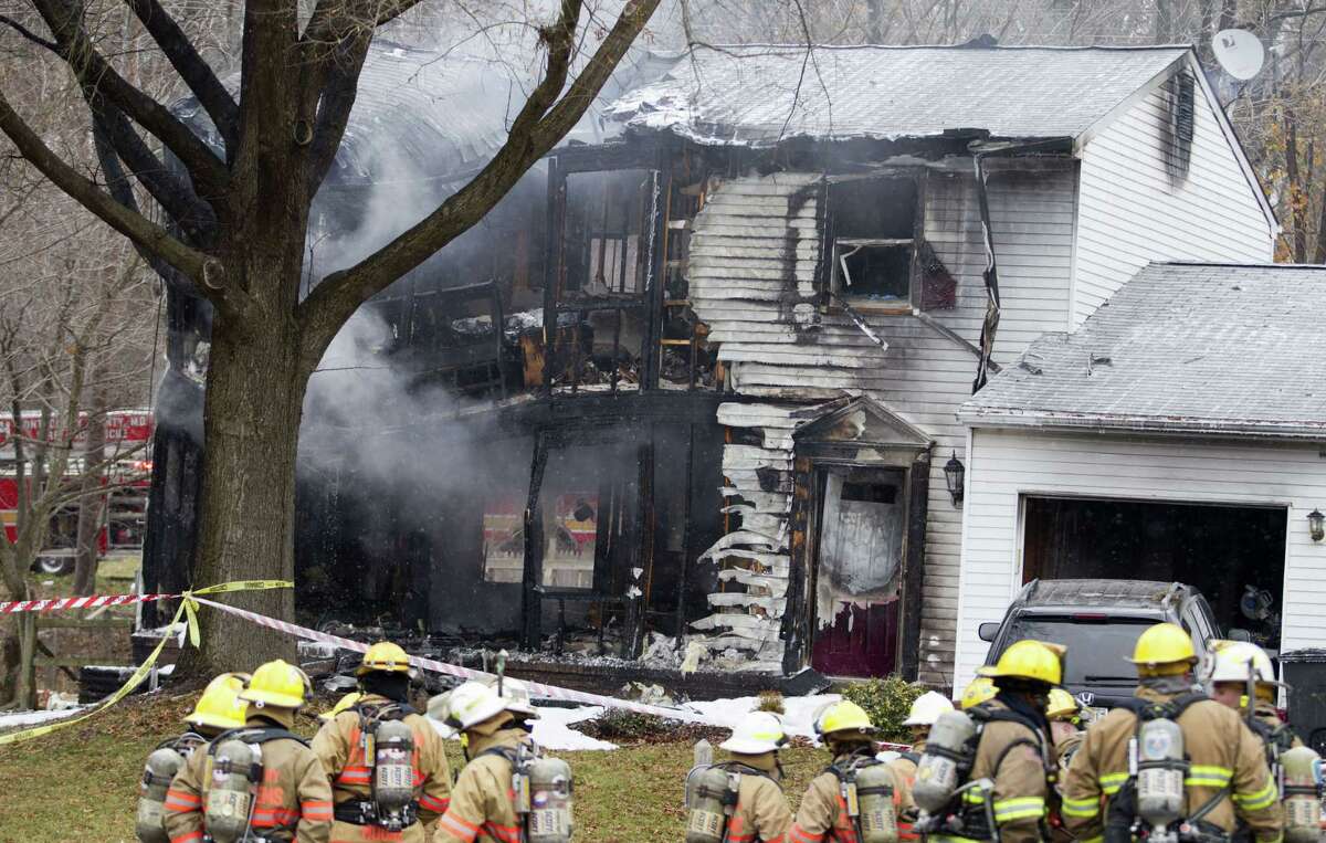 Firefighters stand outside a house in Gaithersbug, Md., Monday, Dec. 8, 2014, where a small plane crashed. A small, private jet has crashed into a house in Maryland's Montgomery County, and a fire official says at least three people on board were killed. (AP Photo/Jose Luis Magana)