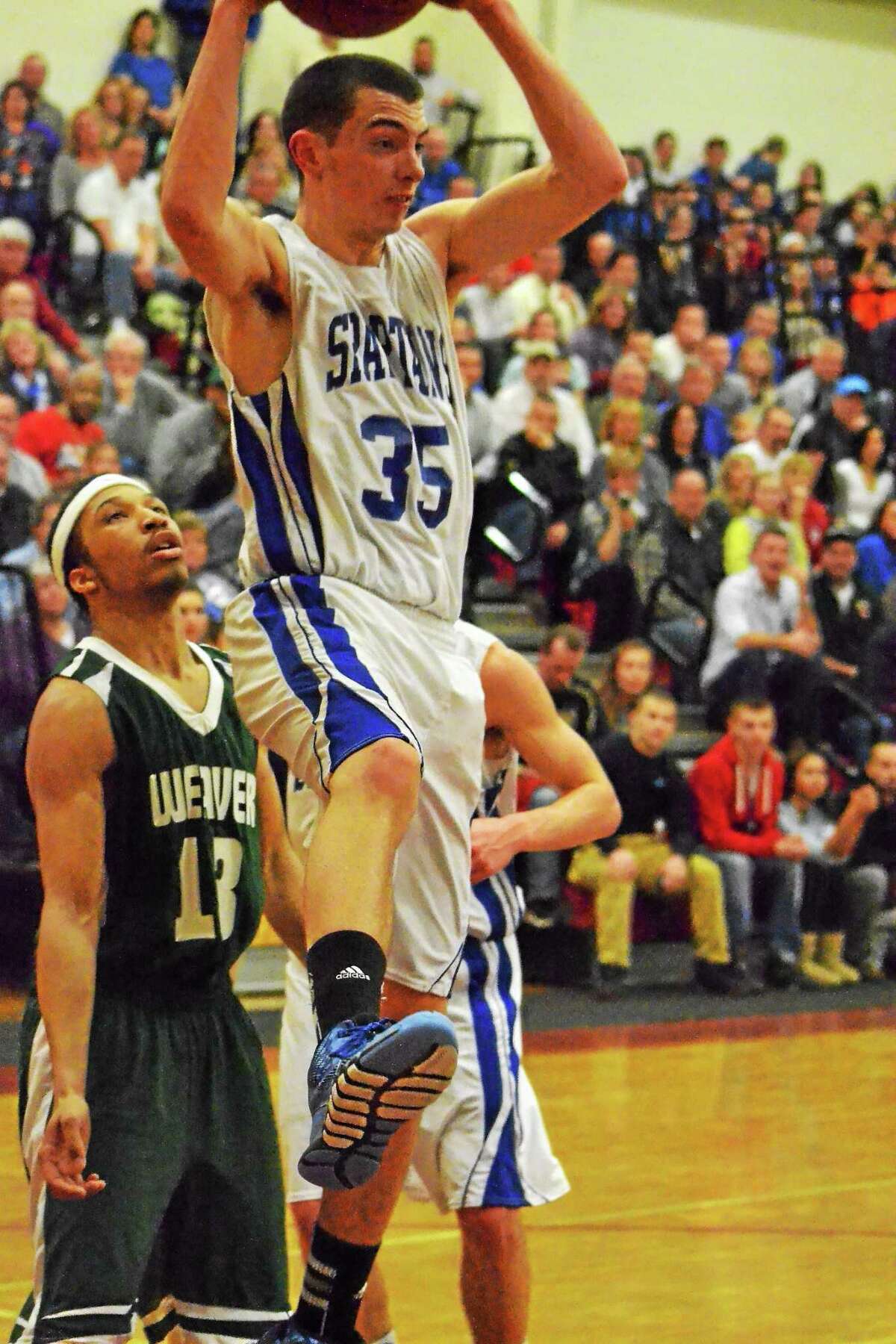 Lewis Mills’ Nate Cook grabs a rebound in the Spartans’ 89-33 loss to Weaver in the Class M semifinals.