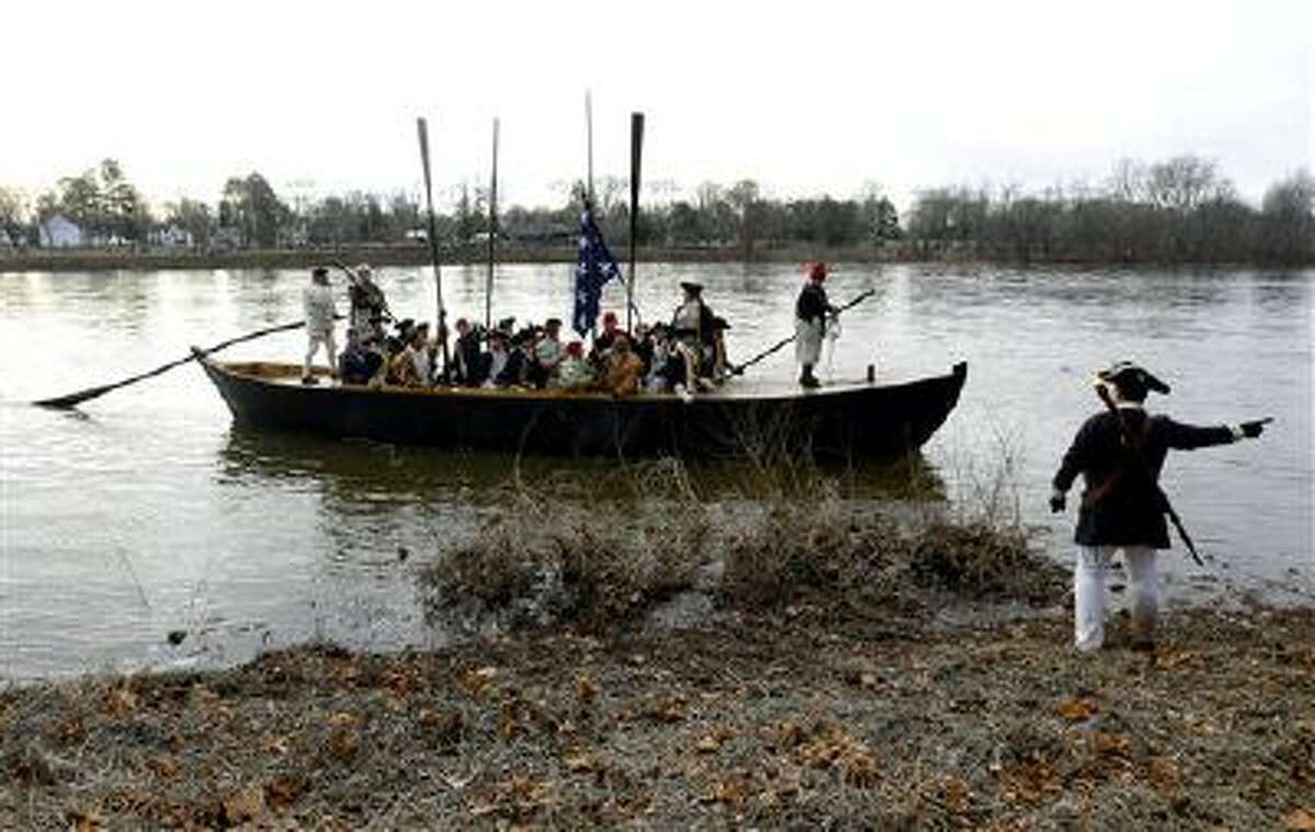 A boat containing George Washington, played by John Godzieba, approaches the riverbank on the New Jersey side after a crew of re-enactors crossed the Delaware River from Pennsylvania during the 61st annual re-enactment of Washington's daring Christmas 1776 river crossing.