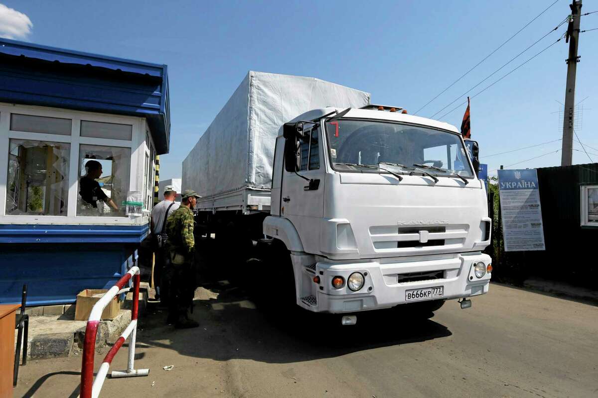 Ukrainian border guards look at the first truck as it passes the border post at Izvaryne, eastern Ukraine, Friday, Aug. 22, 2014. The first trucks in a Russian aid convoy crossed into eastern Ukraine on Friday, seemingly without Kiev's approval, after more than a week's delay amid suspicions the mission was being used as a cover for an invasion by Moscow. (AP Photo/Sergei Grits)