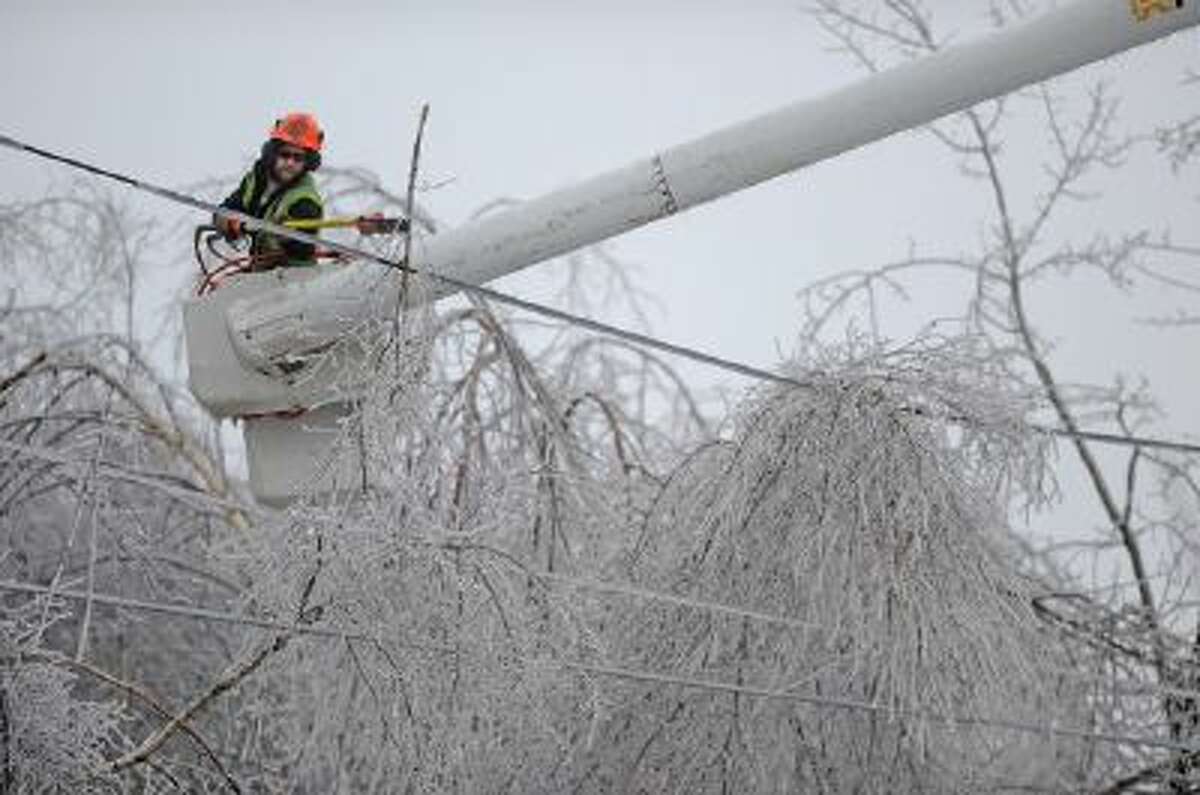 Andrew Powers clears power lines from iced branches in Waterville, Maine, on Monday.