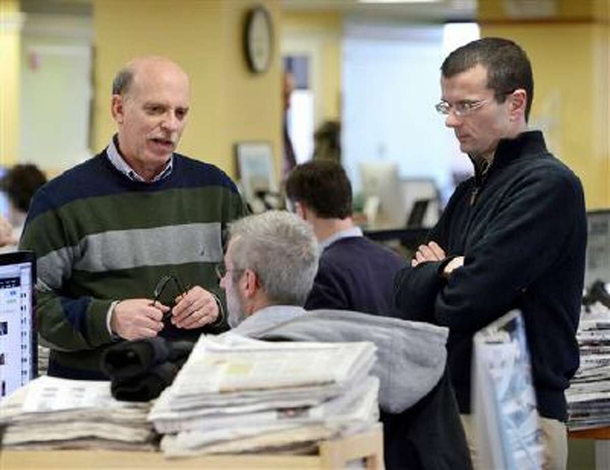 Cliff Schechtman, Portland Press Herald executive editor, left, and Steve Greenlee, managing editor, right, talk with Brian Robitaille, seated, on the copy desk/slot to discuss the next day's front page in Portland, Maine on Tuesday, March 11, 2014. Just three minutes after police officers in the coastal Maine city of Biddeford responded to Derrick Thompson's 911 call and then left the scene, the teenager and his girlfriend were shot dead. But how much were officers told when they were dispatched to Thompson's December 2012 call that he was being threatened? Could they have done more to prevent the killings? Answering questions about their actions took a lawsuit, an appeal and 11 months after state prosecutors turned down the newspaper's request for 911 transcripts. The faceoff was eventually settled in the newspaper's favor by Maine's top court. (AP Photo/Portland Press Herald, John Patriquin)