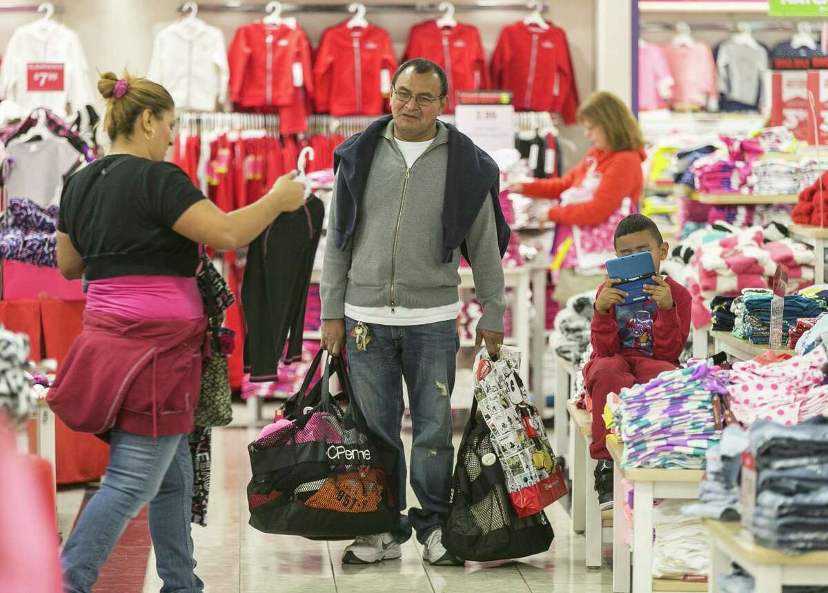 Shoppers Manuel Orellano, center, with his daughter Marcela, left, and her son Manuel, 6, shop for children’s clothing at JCPenney at the Glendale Galleria shopping mall in Glendale, Calif.