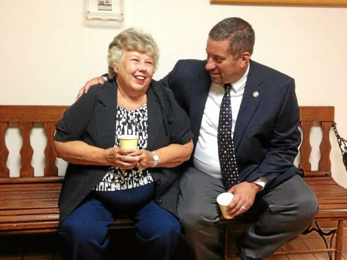 Nancy Arcelaschi sits with State Representative Jay Case after he presented her with the state capitol's flag