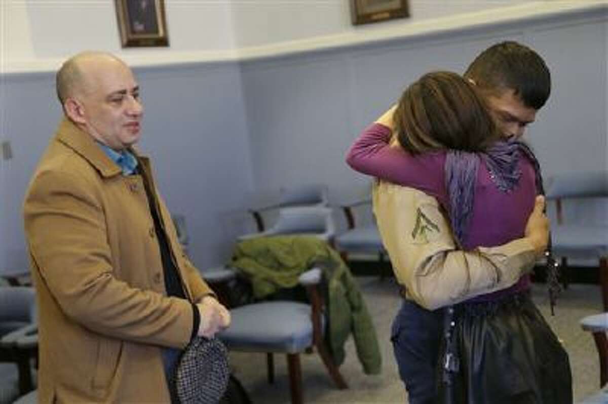 Lance Cpl. Christopher Mohedano-Hernandez, right, is hugged by his sister Kate Mohedano, 12, while his step-father Luis Mohedano looks on after an adoption ceremony in New York.