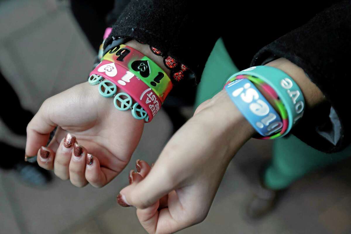 FILE - In this Feb. 20, 2013 file photo, Easton Area School District students Brianna Hawk, 15, left, and Kayla Martinez, 14, display their bracelets for photographers outside the U.S. Courthouse in Philadelphia. A federal appeals court ruled Monday, Aug. 5, 2013 that a Pennsylvania school district cannot ban "I (heart) Boobies!" bracelets, rejecting the district's claim that the slogan — designed to promote breast cancer awareness among young people — is lewd. The ruling is a victory for Hawk and Martinez, who challenged the school rule in 2010 with help from the American Civil Liberties Union. Easton is one of several school districts around the country to ban the bracelets, which are distributed by the nonprofit Keep A Breast Foundation of Carlsbad, Calif. (AP Photo/Matt Rourke, File)