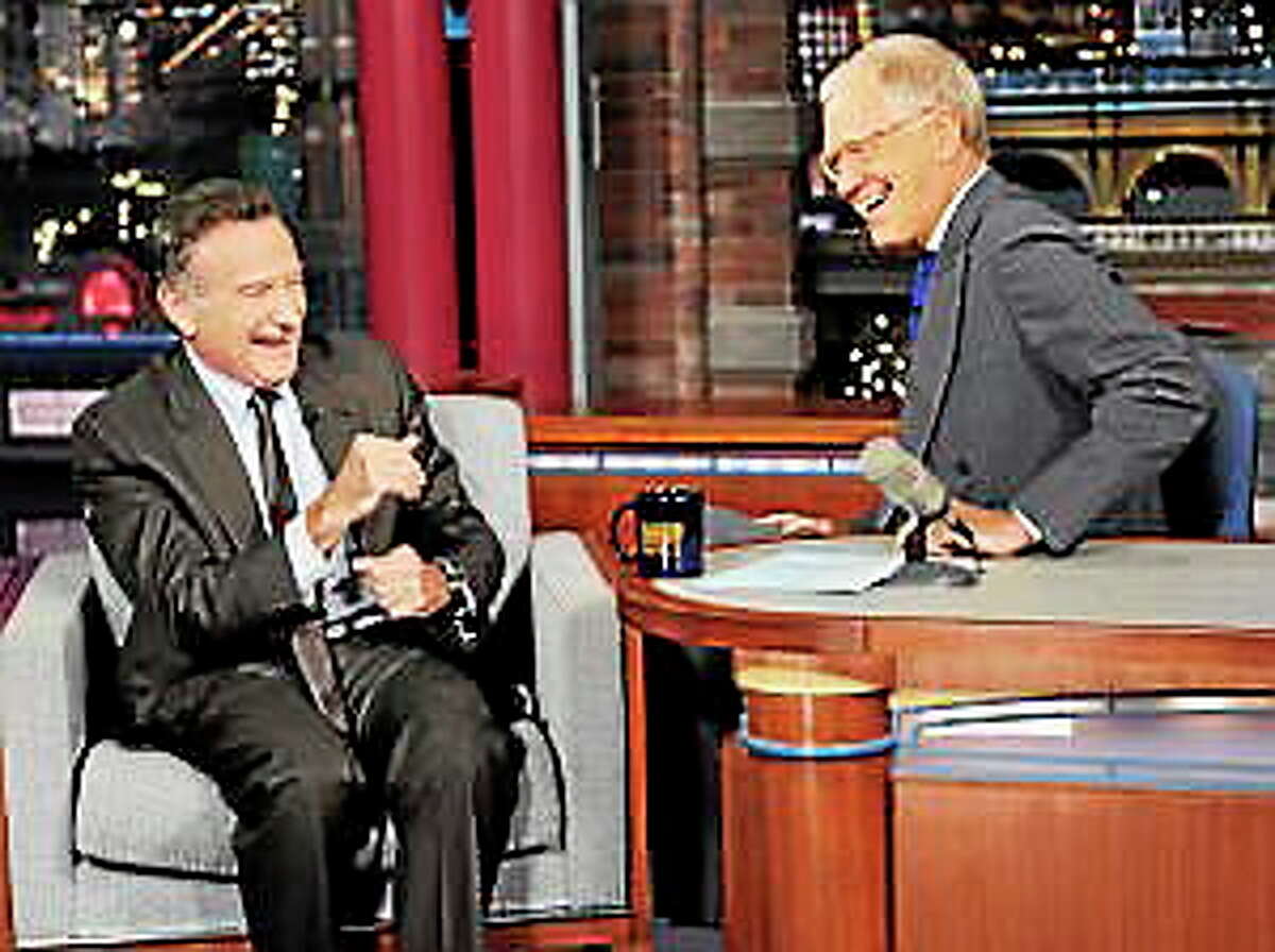 In this Wednesday, Sept. 25, 2013 photo provided by CBS, actor Robin Williams, left, joins host David Letterman on the set of the “Late Show with David Letterman,” in New York. CBS says Letterman has signed a contract extension to remain host of the “Late Show” into 2015.