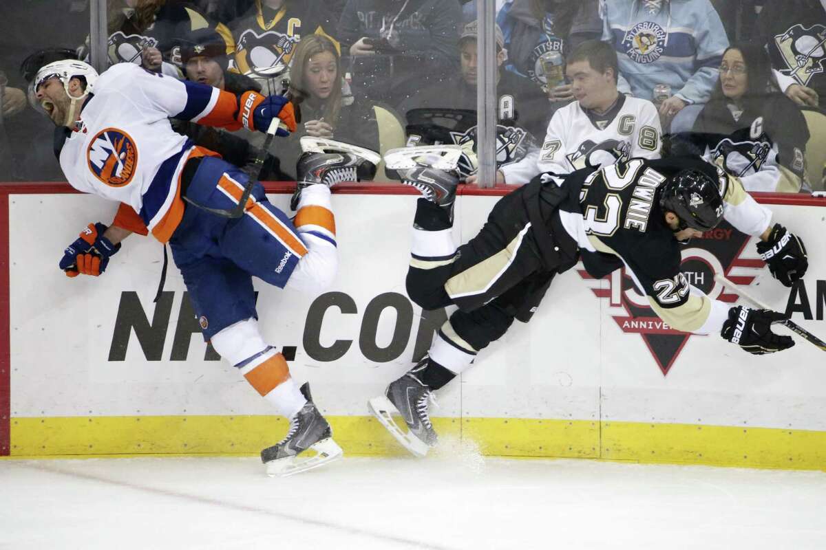 The Penguins’ Steve Downie collides with the New York Islanders’ Johnny Boychuk, left, along the boards during the third period of a Nov. 21 game in Pittsburgh.