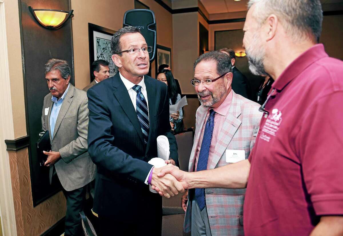 Connecticut Governor Dannel P. Malloy (center) shakes hands with Chip Beckett, Vice Chairman of the Capitol Region Council of Governments, at a Transportation Forum in North Haven, Connecticut, on Monday September 15, 2014.