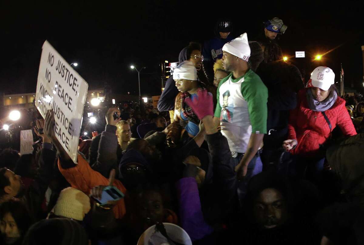 FILE - In this Nov. 24, 2014 file photo Louis Head, center right, Michael Brown's stepfather, and Brown's mother Lesley McSpadden, center left, react as they listen to the announcement that a grand jury decided not to indict Ferguson police officer Darren Wilson who fatally shot 18-year-old Brown. Brown has apologized for angry comments he made after the decision was announced, but said his remarks had nothing to do with the arson and looting that ravaged Ferguson and the surrounding area. (AP Photo/Charlie Riedel, File)