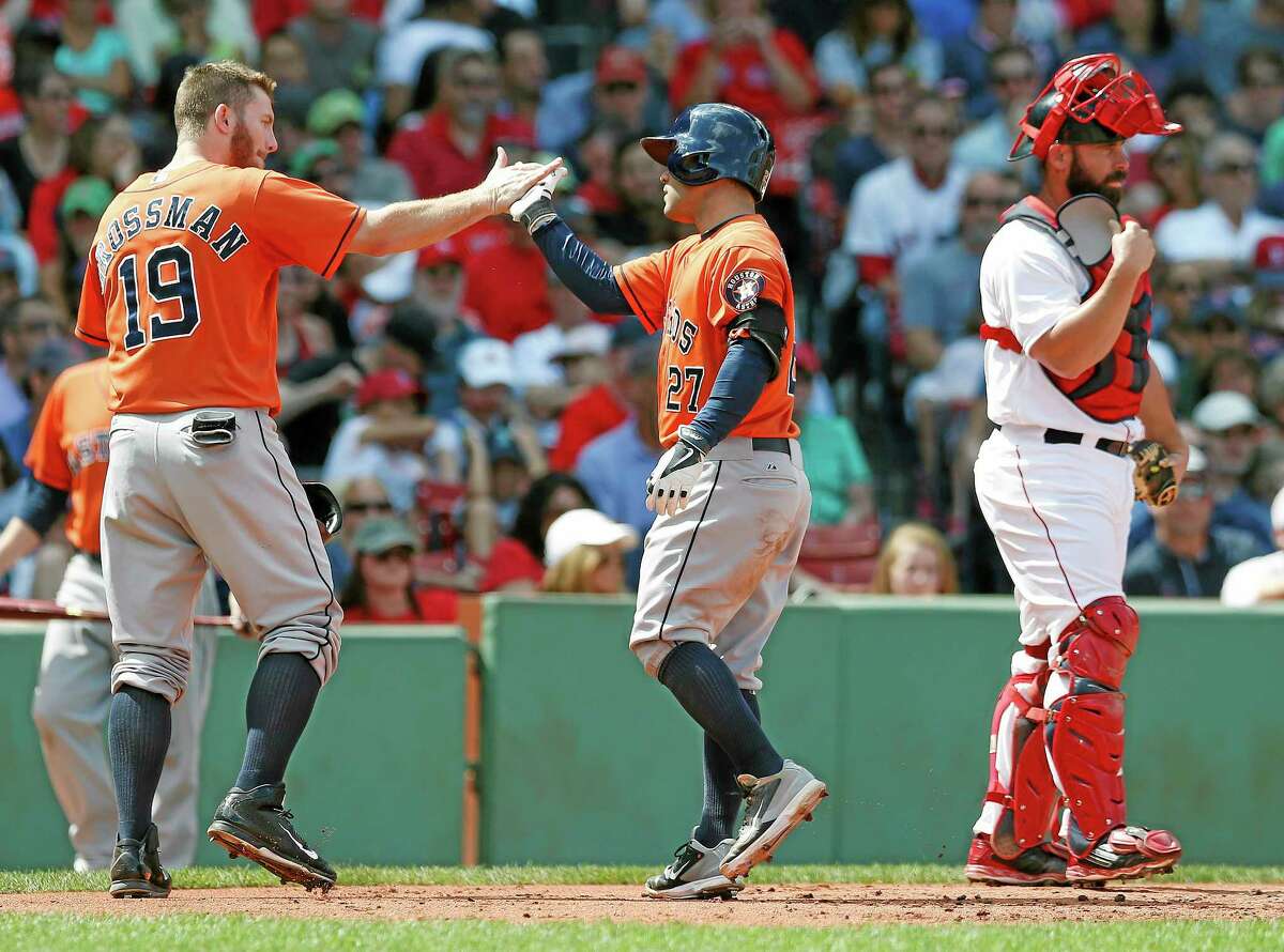 The Astros’ Jose Altuve (27) celebrates his grand slam behind Red Sox catcher Dan Butler, right, in the second inning on Sunday.