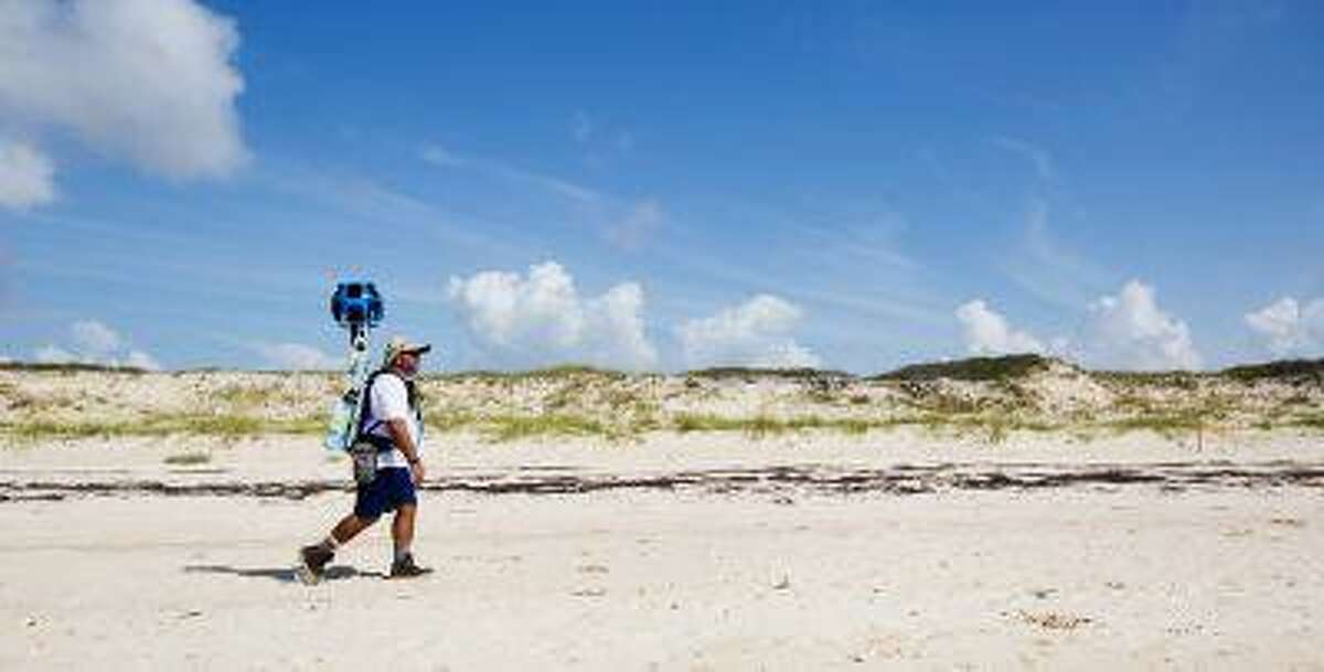In this photo taken July 30, 2013, and made available by Visit Florida, Gregg Matthews carries a Google street view camera as he walks recording St. George Island sand dunes in the Florida Panhandle. Visit Florida, the state's tourism agency, partnered with Google in the effort to map all 825 miles of Florida's beaches. The Florida project is the first large-scale beach mapping project. (AP Photo/Visit Florida, Colin Hackley)