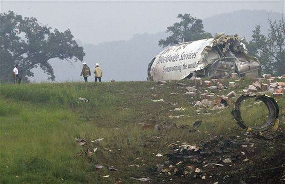 Fire crews investigate where a UPS cargo plane lies on a hill at Birmingham-Shuttlesworth International Airport after crashing on approach, Wednesday, Aug. 14, 2013, in Birmingham, Ala. Toni Herrera-Bast, a spokeswoman for Birmingham's airport authority, says there are no homes in the immediate area of the crash. (AP Photo/Butch Dill)