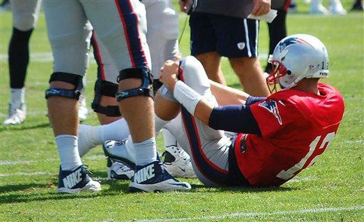 New England Patriots quarterback Tom Brady grabs his left knee after an apparent injury during a joint workout with the Tampa Bay Buccaneers at NFL football training camp, in Foxborough, Mass., Wednesday, Aug. 14, 2013. (AP Photo/Will DiTullio)