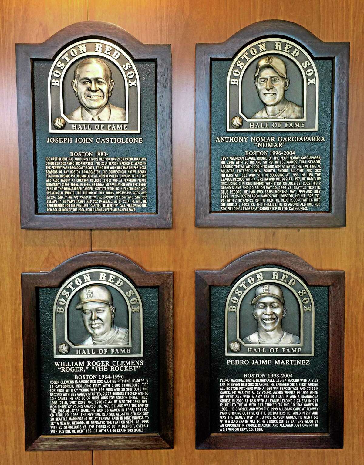 Plaques for 2014 Boston Red Sox Hall of Fame inductees hang at Fenway Park Thursday, Aug. 14, 2014 in Boston. Clockwise from top left are plaques honoring broadcaster Joe Castiglione, shortstop Nomar Garciaparra, pitcher Pedro Martinez and pitcher Roger Clemens. The four men will be honored before Thurday night's game against the Houston Astros. (AP Photo/Jimmy Golen)